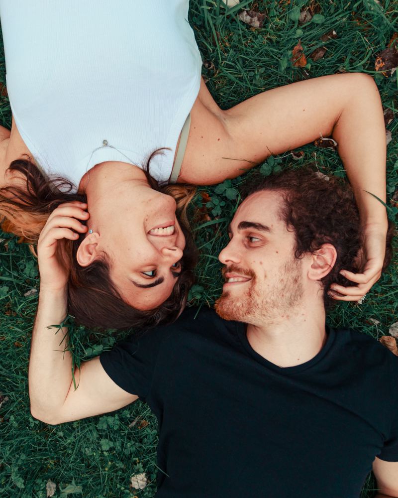 Couple d'amoureux allong� dans l'herbe, t�te contre t�te