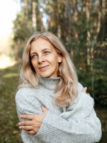 Femme blonde en pull dans une forêt d'automne