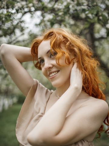 Femme rousse souriante dans un jardin