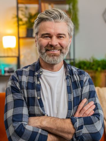 Homme aux cheveux gris souriant chez lui