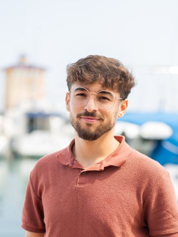 Jeune homme souriant au bord d'un port